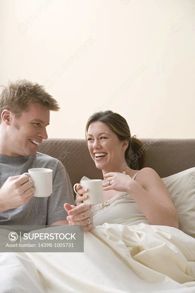 Happy couple having coffee in bed