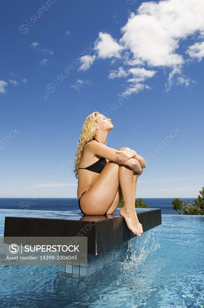 Woman sitting on platform in pool