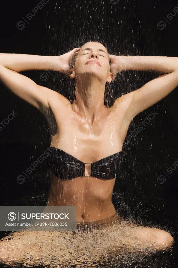 Woman sitting under shower of water