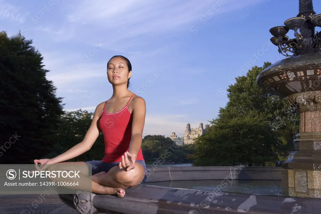 Woman meditating by fountain