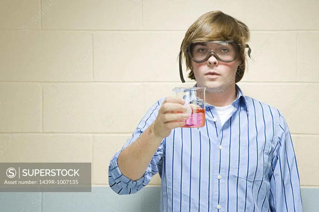 Male student holding chemical in flask