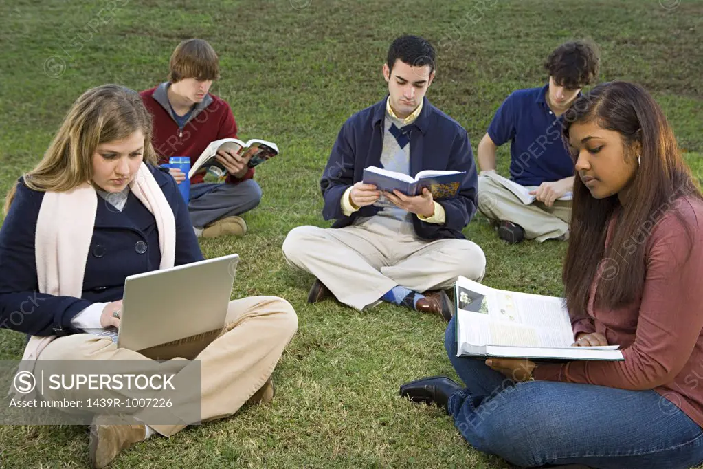 Five students sat reading outdoors