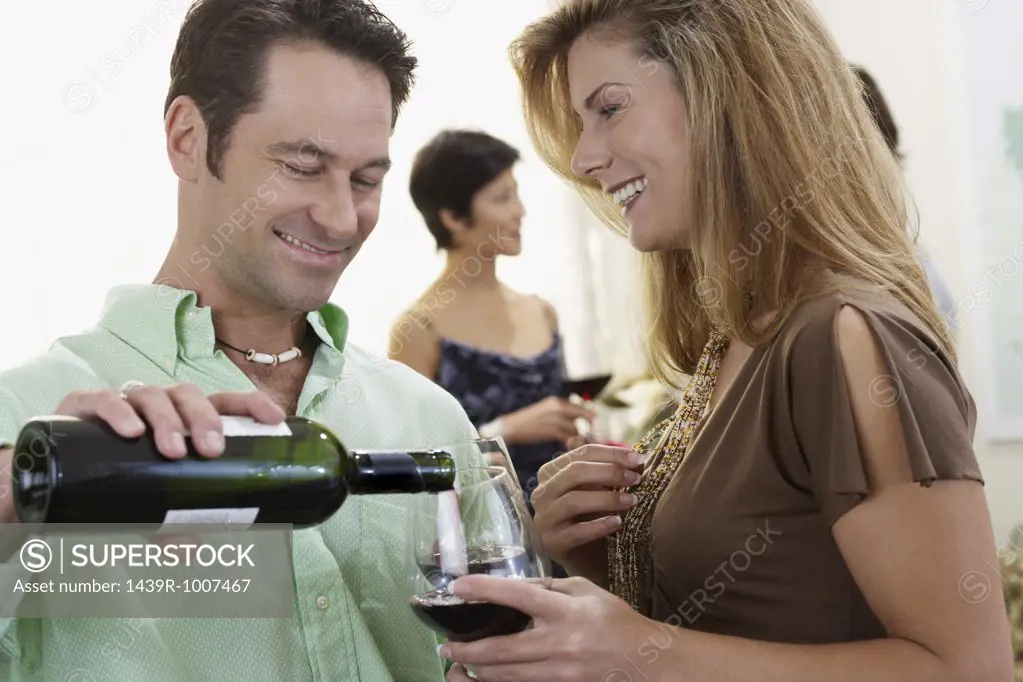 Host pouring wine for woman