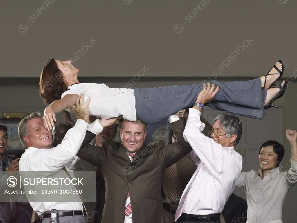 Office workers lifting colleague