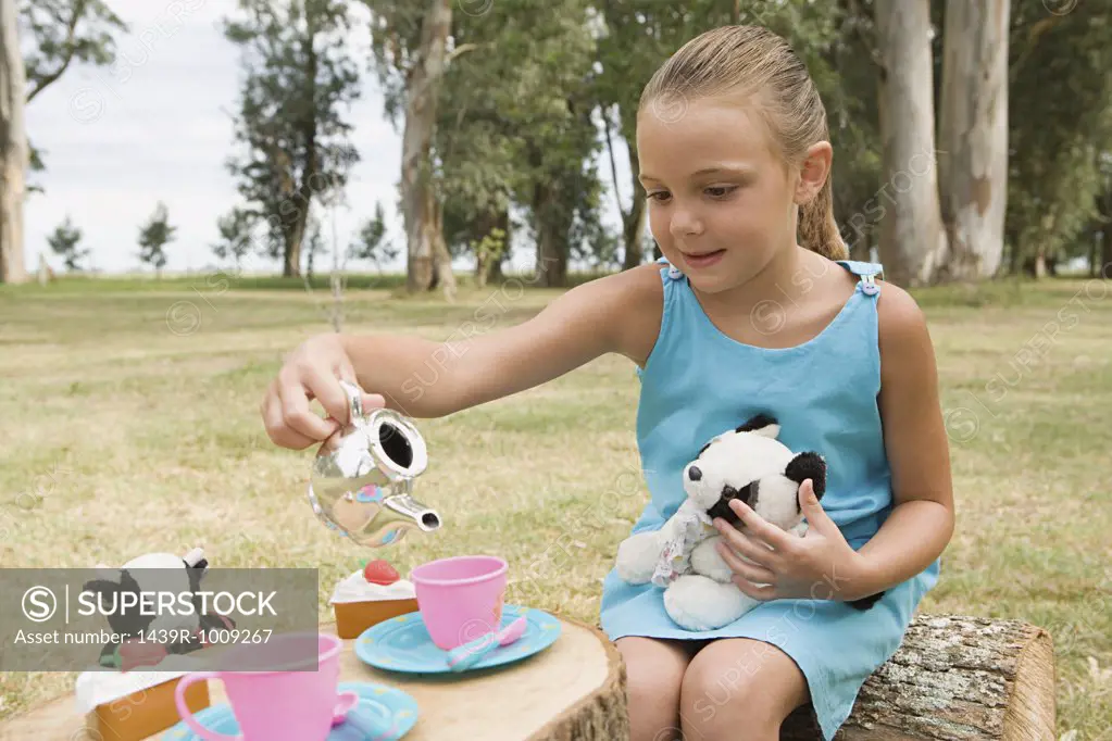 Girl having a tea party with soft toys