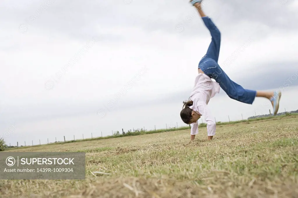 Girl doing a cartwheel in a field