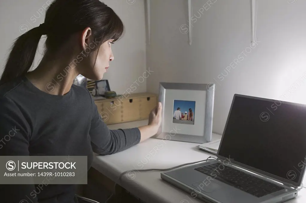 Woman at desk looking at photograph