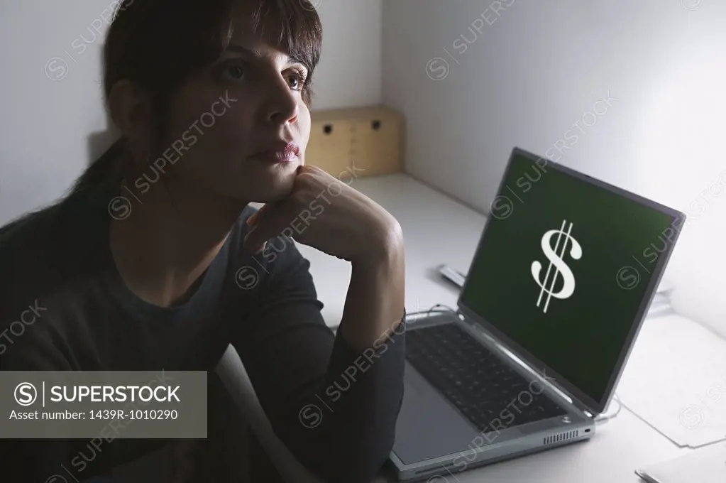 Woman daydreaming with dollar sign on her laptop