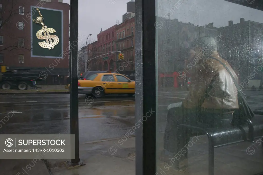 Man looking at billboard from bus shelter