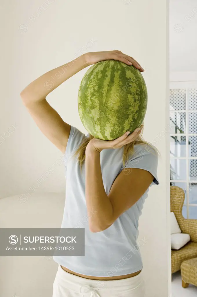 Woman holding watermelon over face
