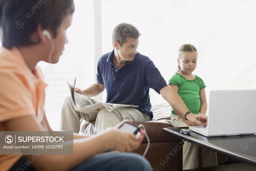 Father helping daughter use laptop