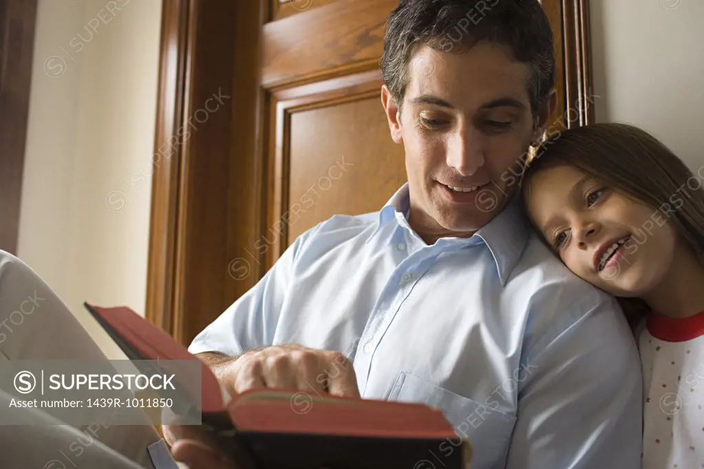 Father reading bible with daughter