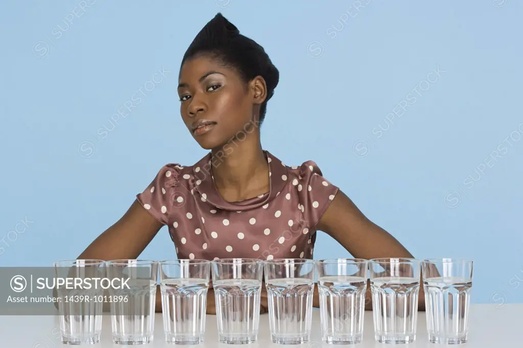 Young woman with eight glasses of water