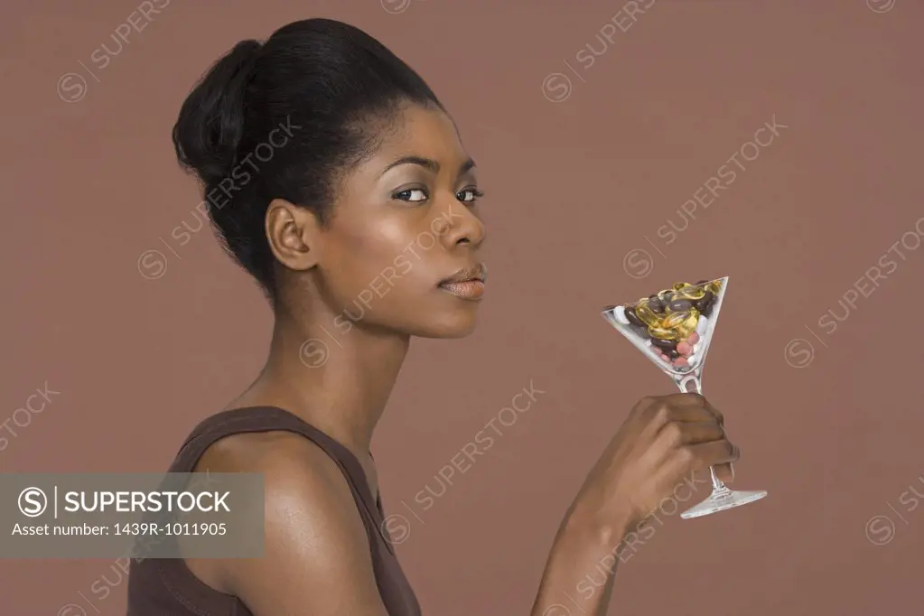 Young woman holding a cocktail glass full of vitamins