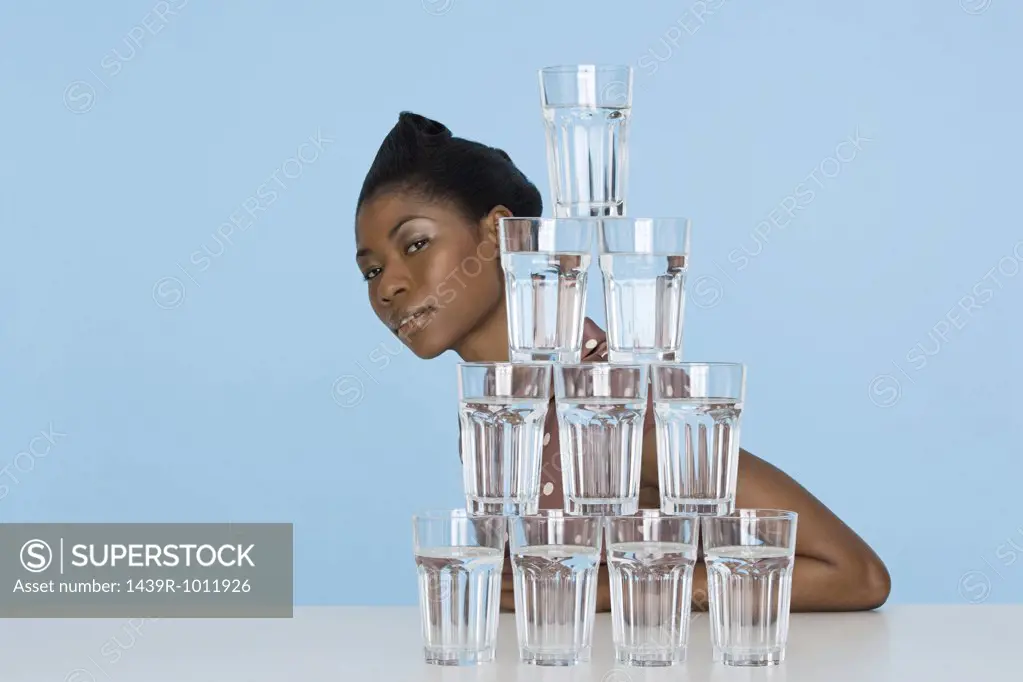 Young woman behind a stack of glasses