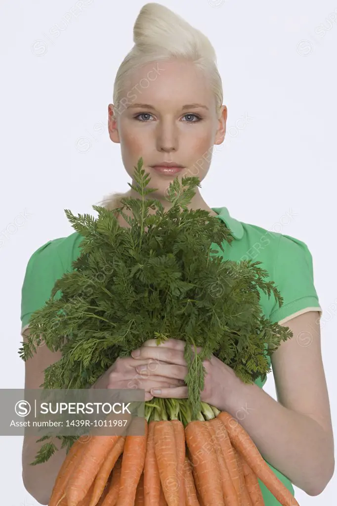 Young woman holding carrots