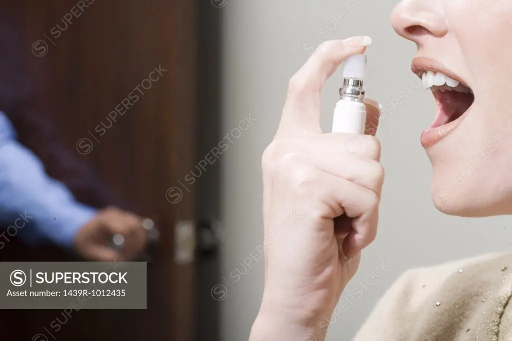 Woman spraying breath freshener