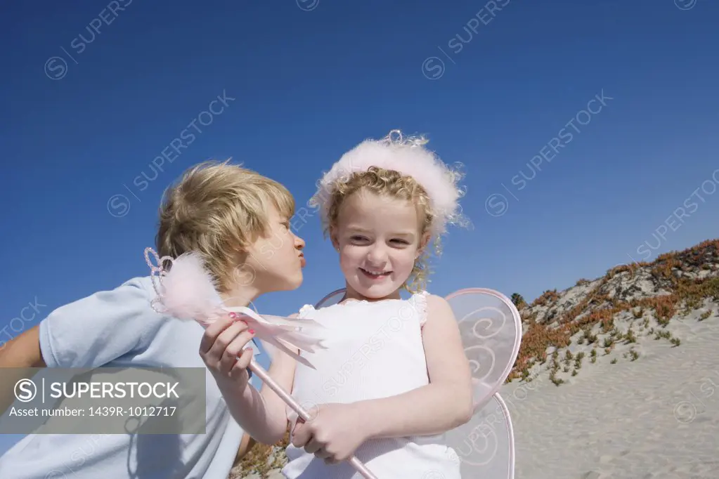 Girl wearing costume with boy on beach