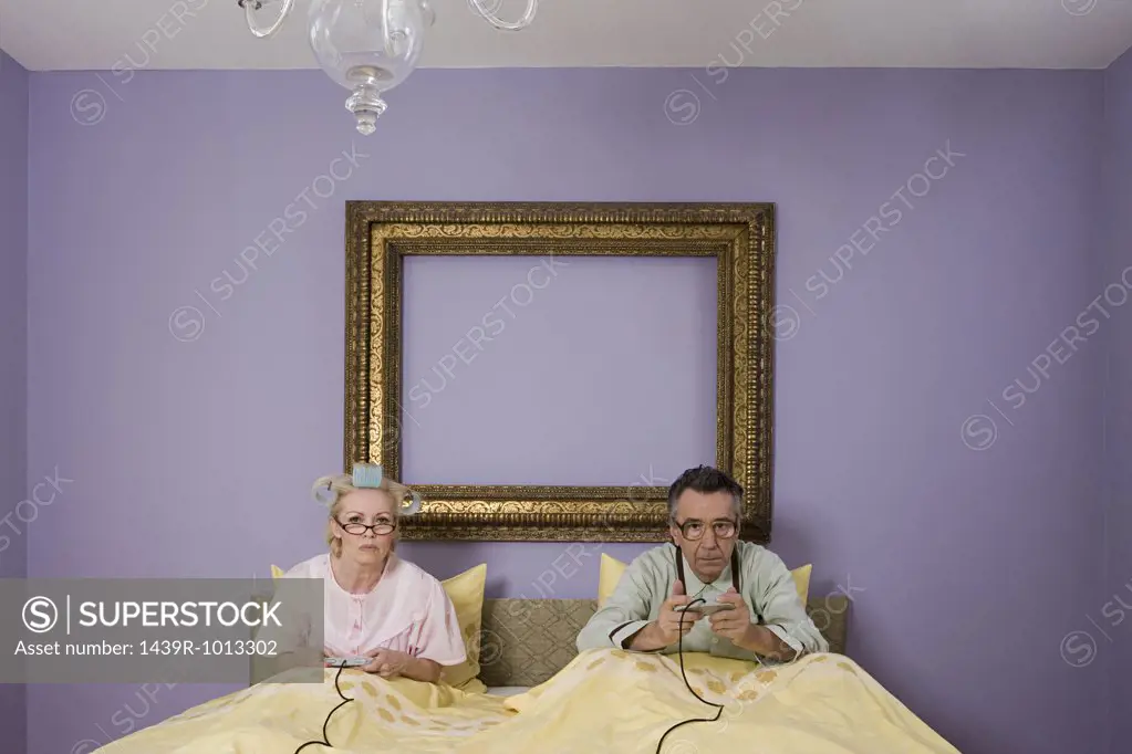 Senior couple playing video game in bed