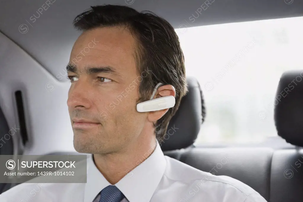 Businessman with bluetooth headset sitting in car