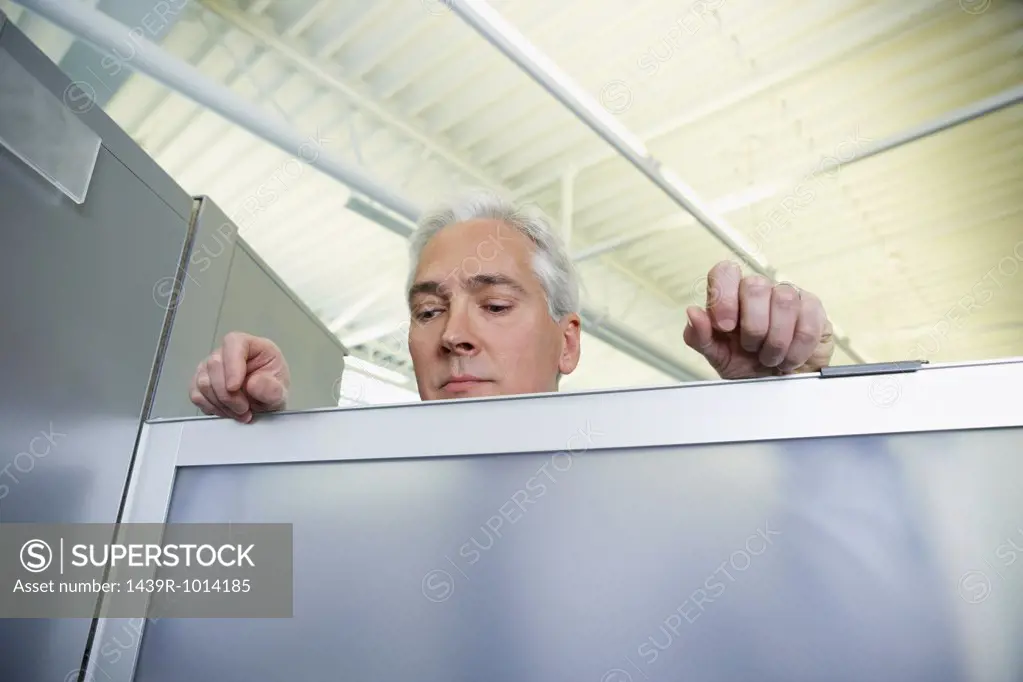 Man peering over a glass partition