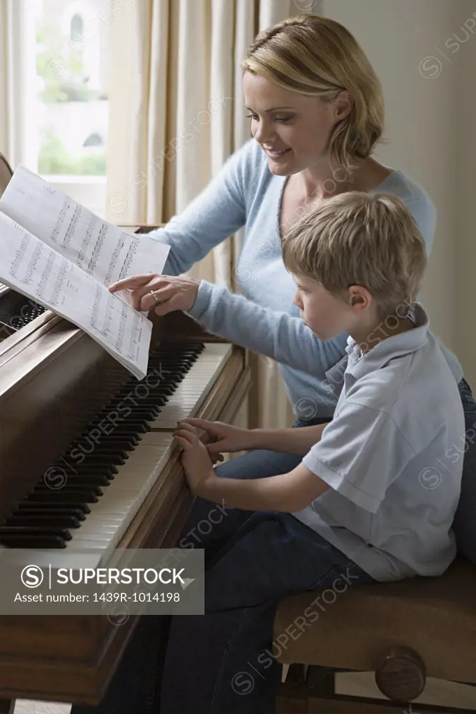 Mother teaching piano to son