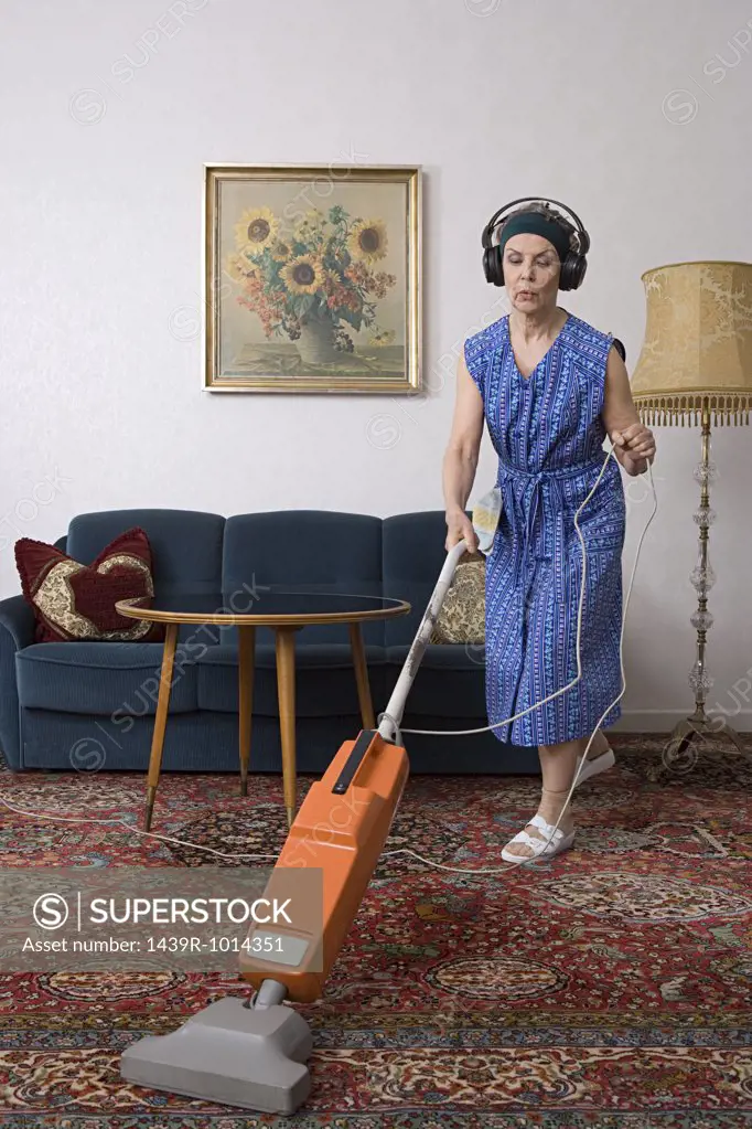Woman wearing headphones and vacuuming