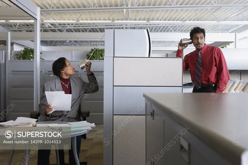Two office workers using a tin can telephone