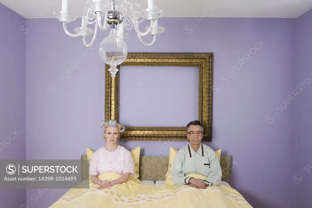 Couple in bed looking miserable