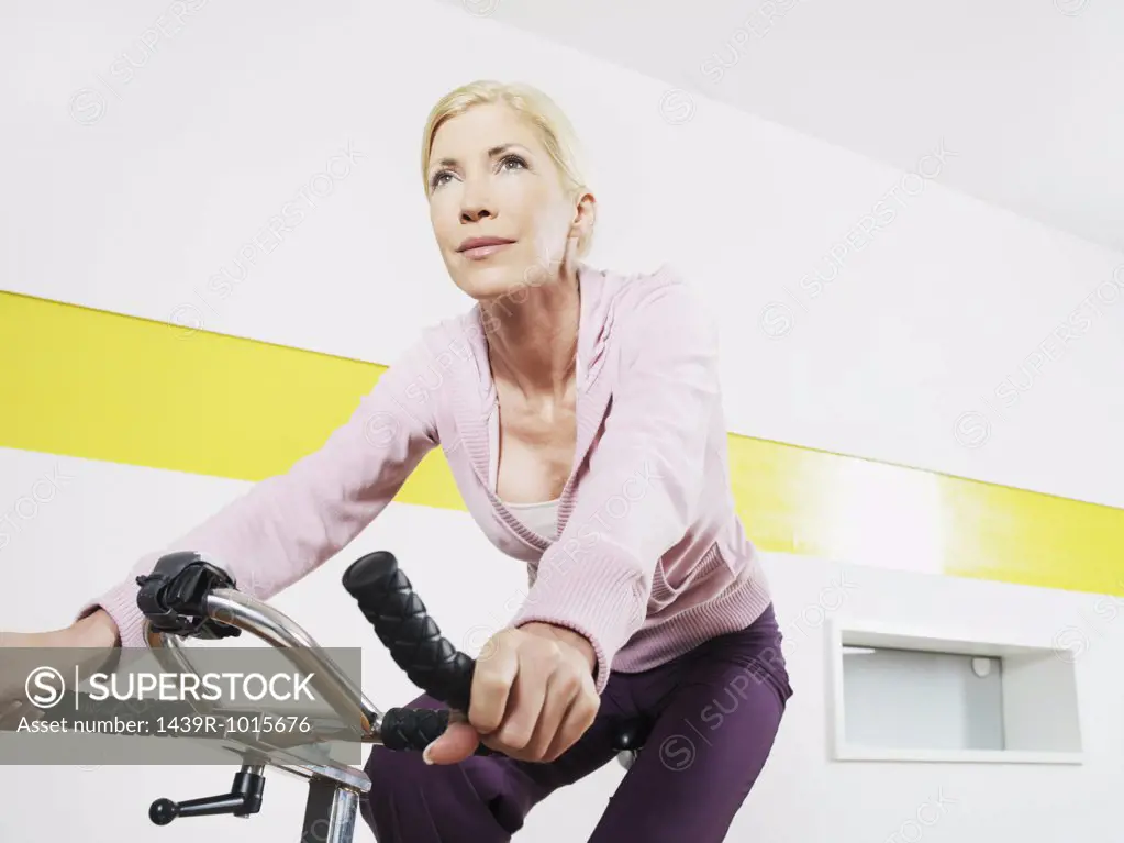 Woman exercising cycling in health club 