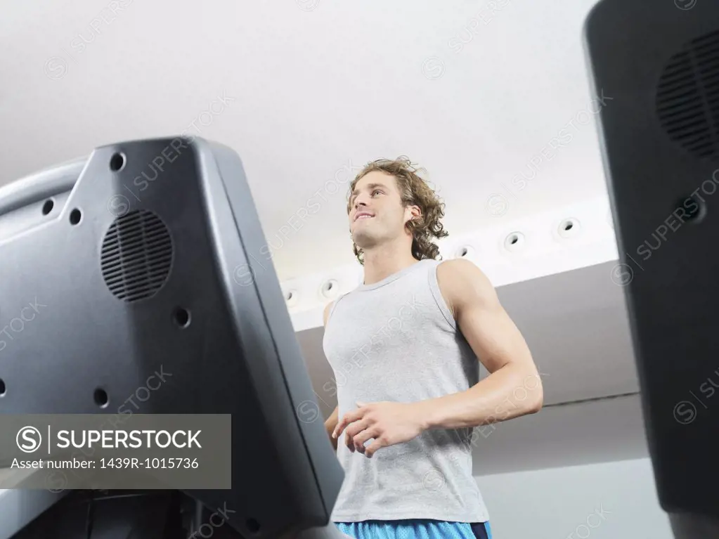 Mann on treadmill in health club 