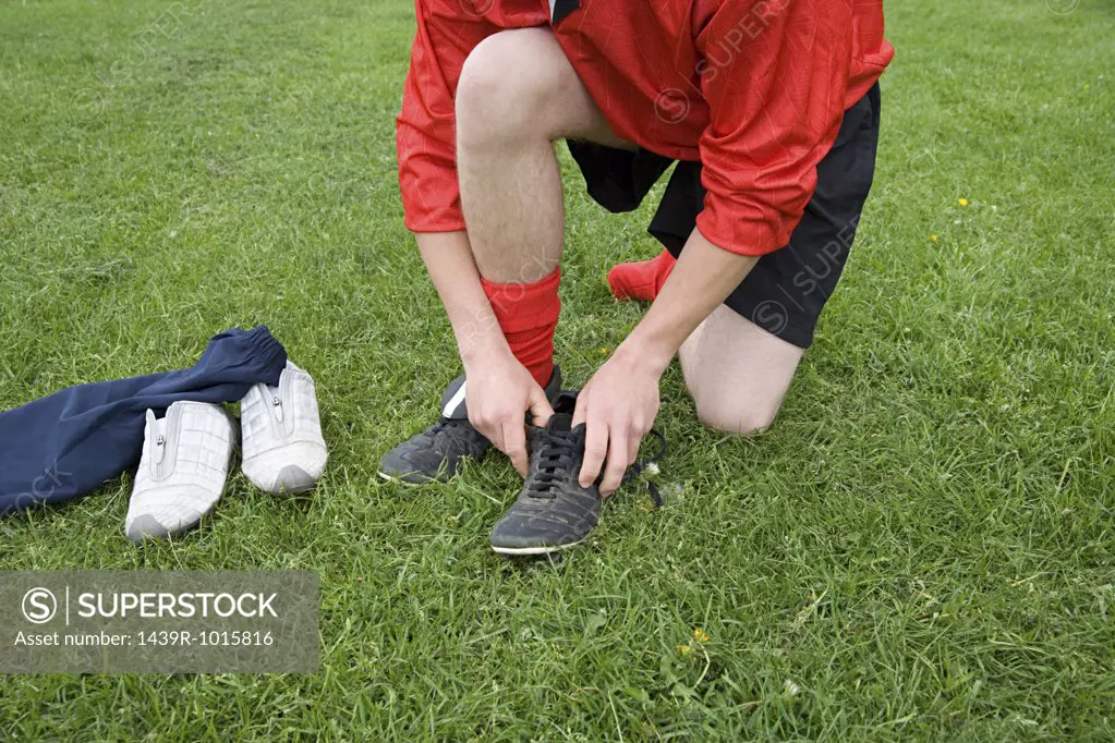 Footballer putting boots on