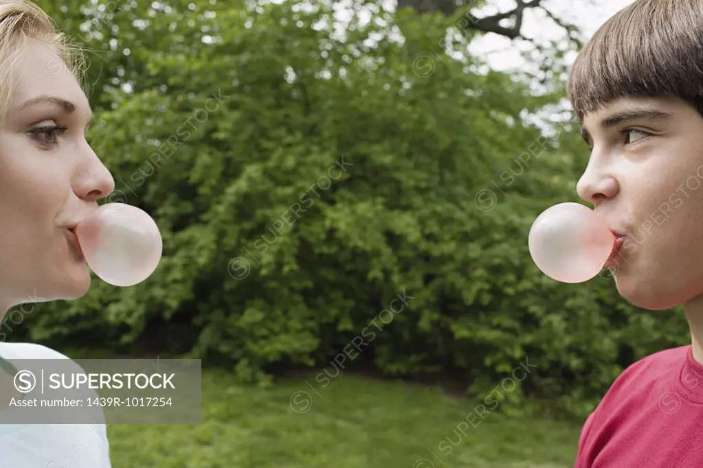 Teenage couple blowing bubble gum bubbles