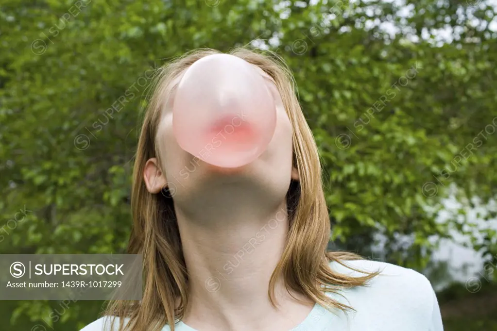 Teenage girl blowing a bubble gum bubble
