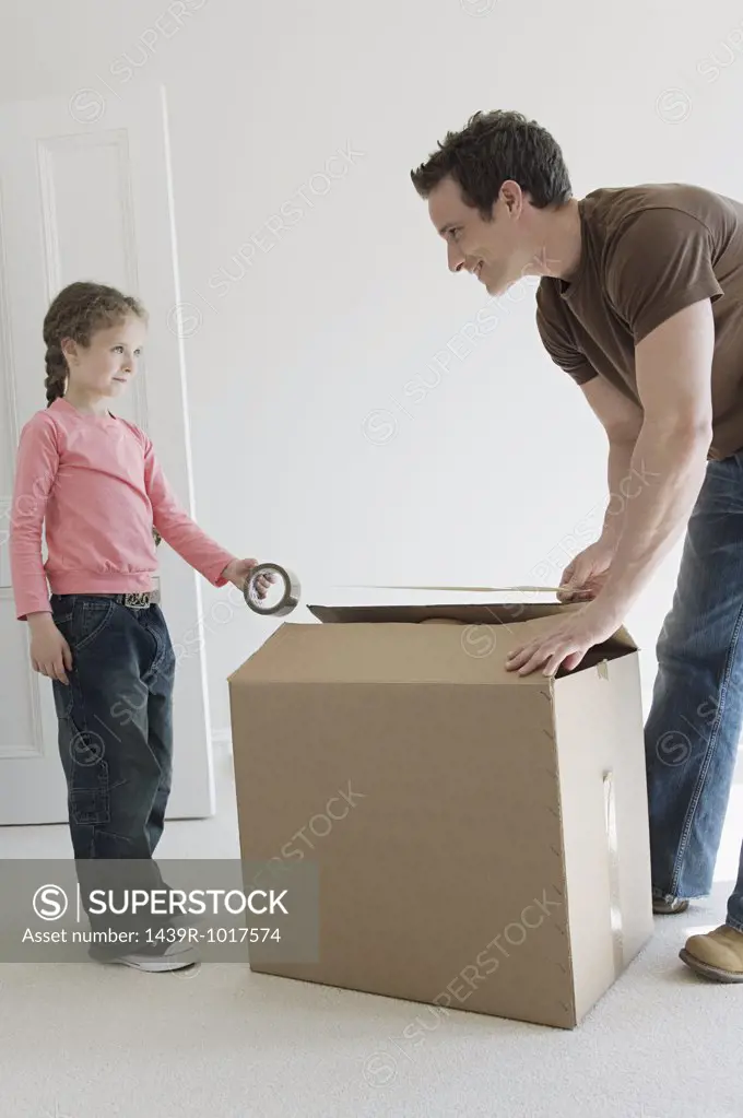 Father and daughter taping up box