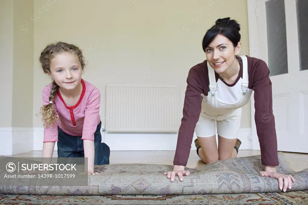 Mother and daughter rolling rug