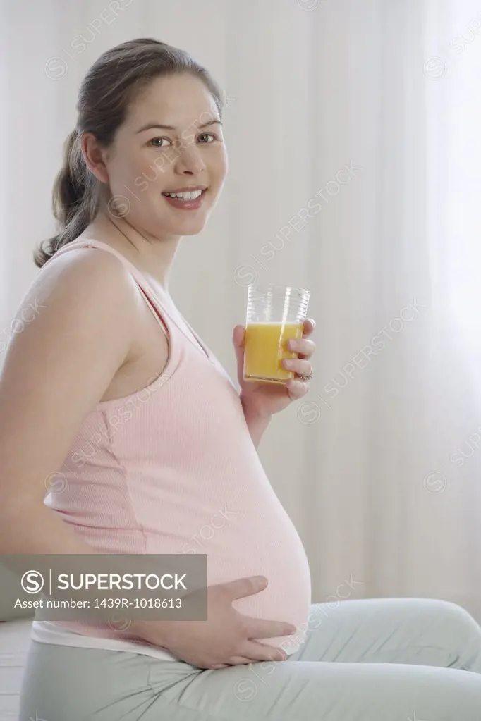 Pregnant woman holding glass of orange juice
