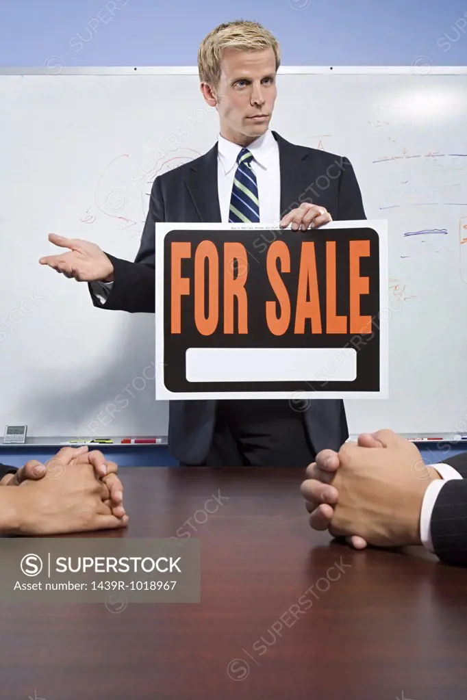 Businessman holding for sale sign