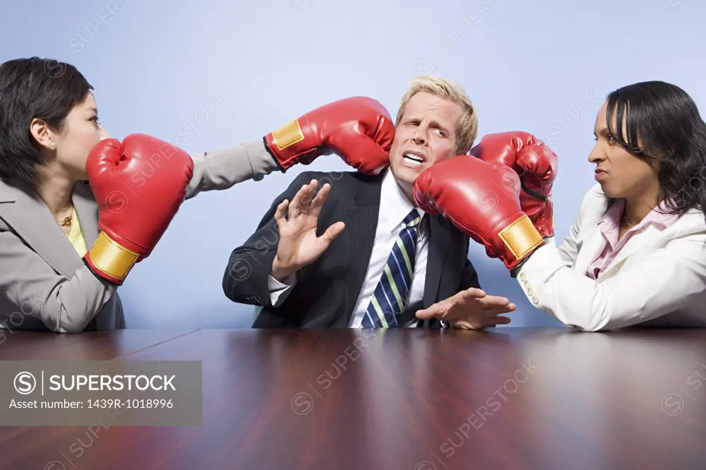 Two businesswomen punching a businessman