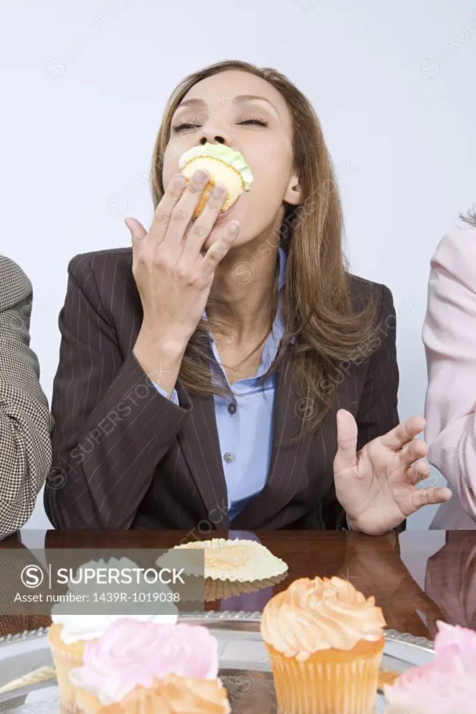 Businesswoman eating cupcake