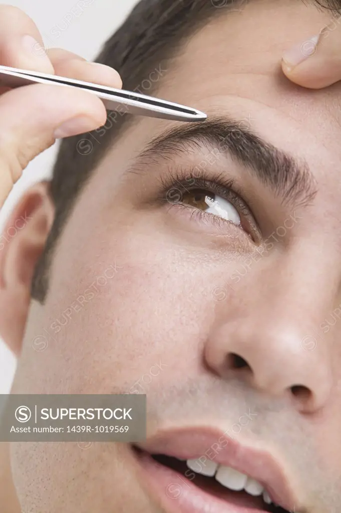 Man plucking his eyebrows