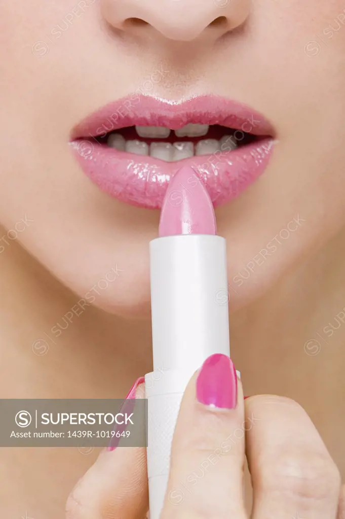 Woman applying pink lipstick