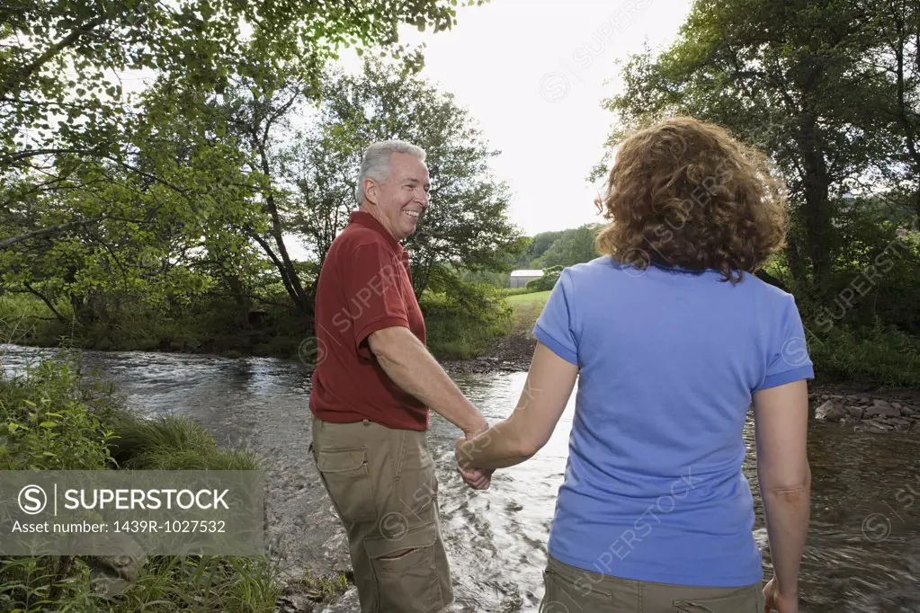 Mature couple crossing a stream
