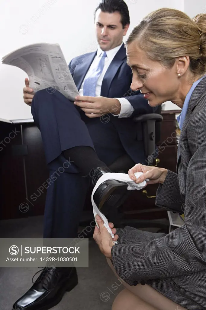 Woman polishing businessmans shoe
