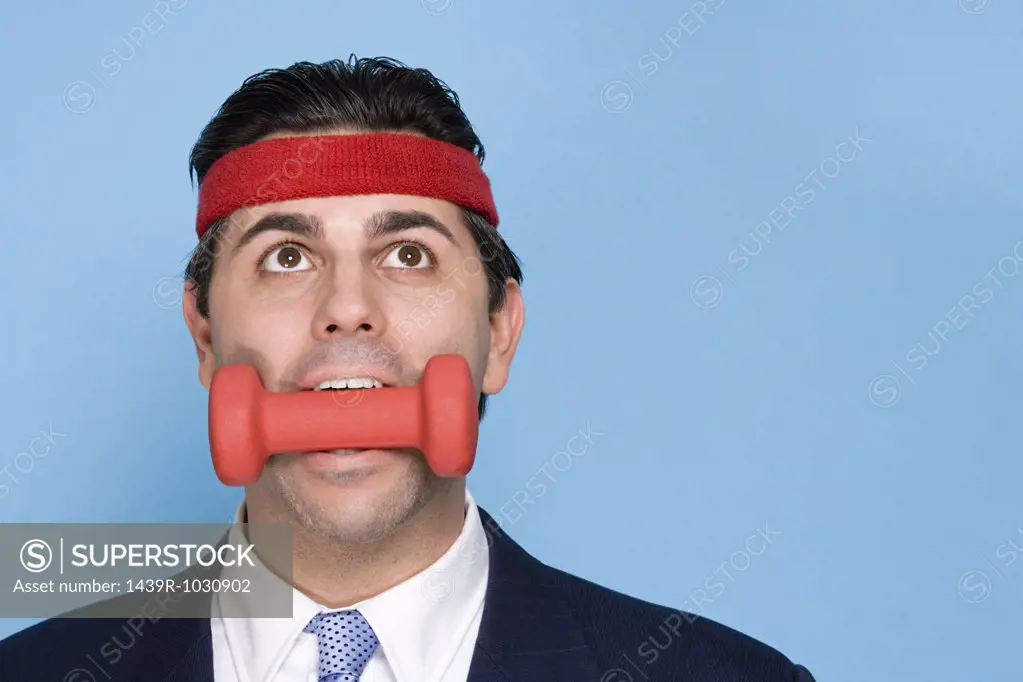 Businessman with a dumbbell in mouth