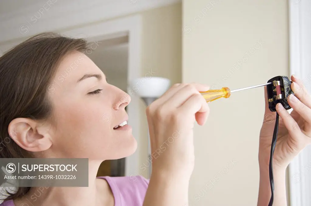 Woman changing fuse on a plug