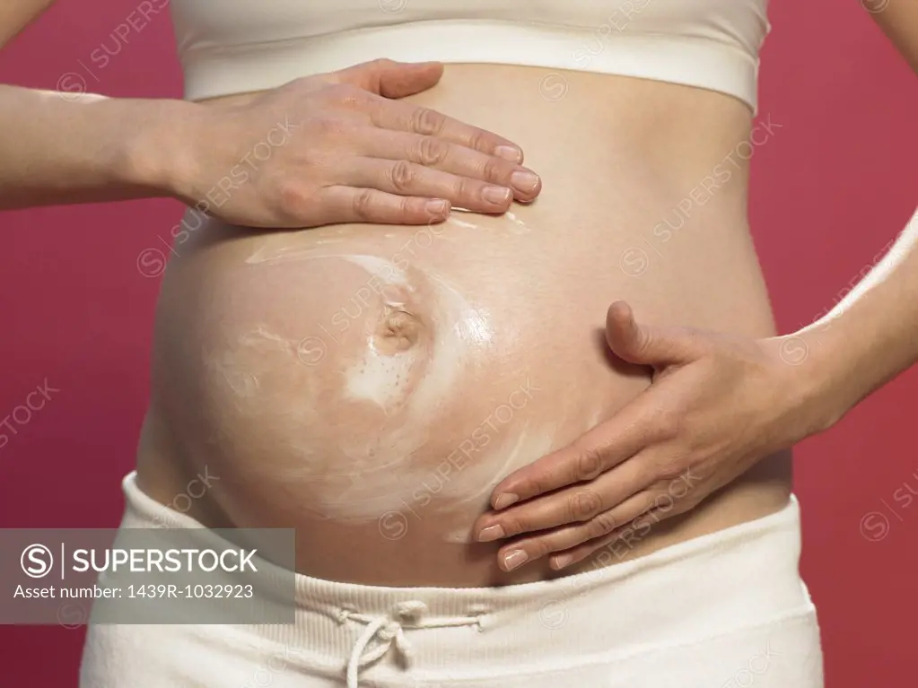 Pregnant woman applying moisturiser