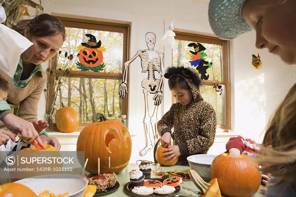 Woman and kids carving pumpkins