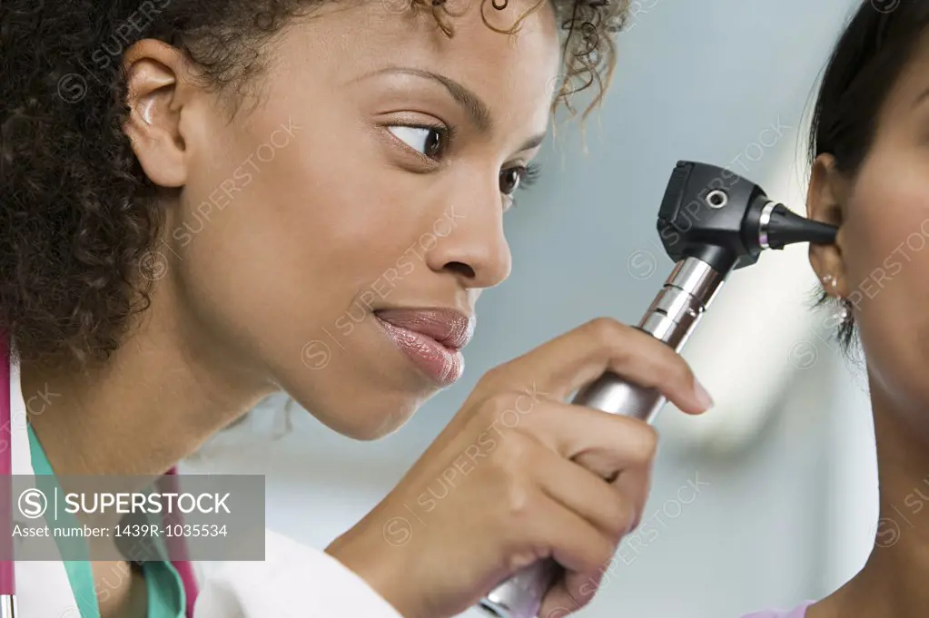 Doctor examining patient with otoscope