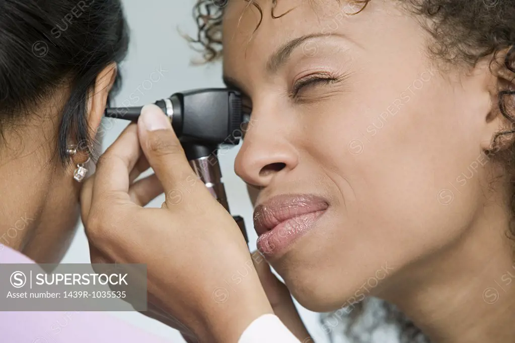 Doctor examining patient with otoscope